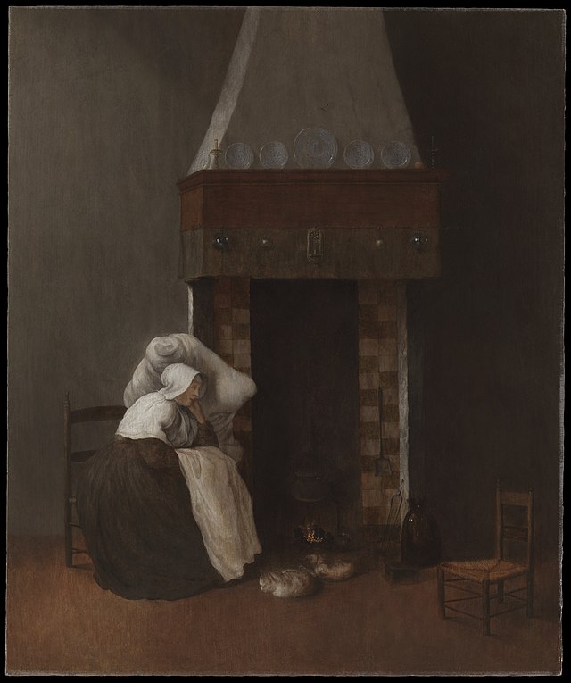A woman sits next to a fireplace with her head resting against a pillow which is propped up on the wall.